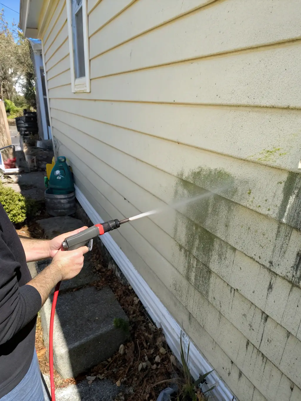 The siding of a house being gently pressure washed, demonstrating the safe and effective cleaning process used by Pressure-Pro Washing Services.
